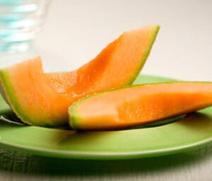 Cantaloupe slices on a green plate