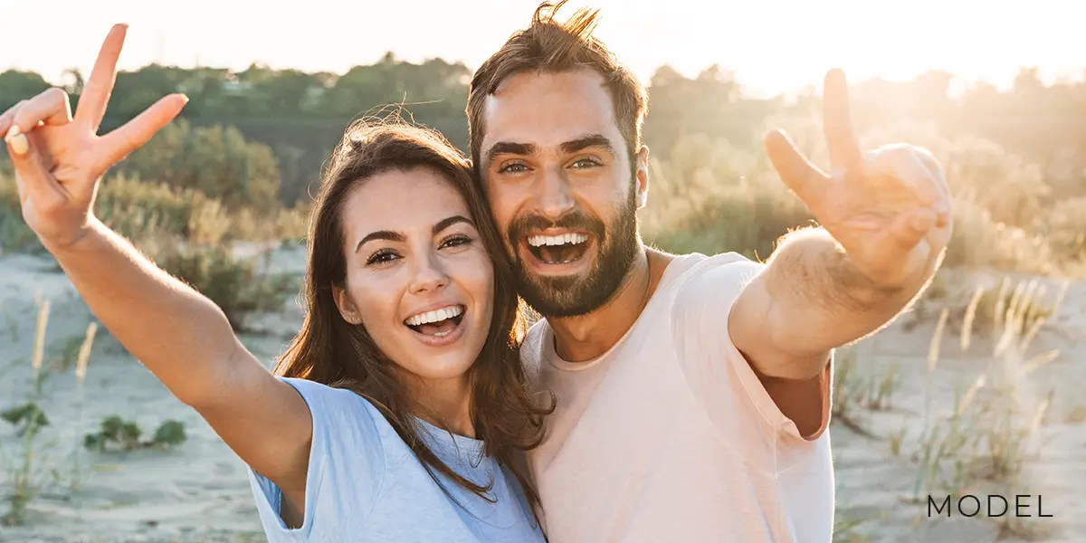 Happy Couple Outdoors Showing a Peace Sign