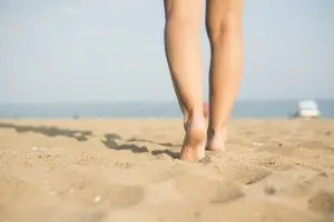 Legs Free from Vericose Veins Walk Along a Beach