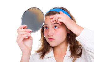 Teenager girl examine her pimples in the mirror