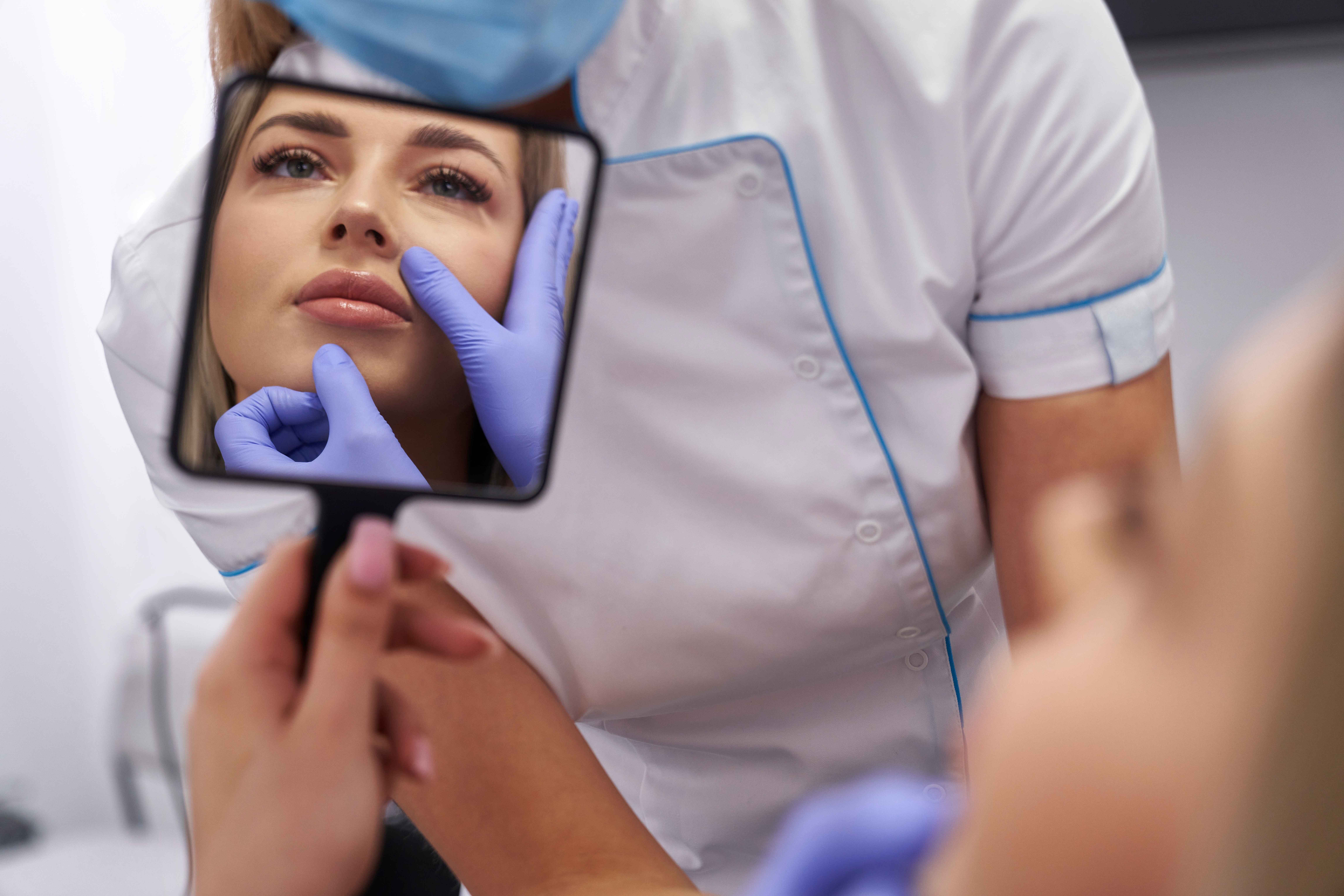 woman looking at herself in a mirror after a med spa treatment